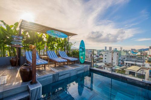 a swimming pool with chairs and a surfboard on a building at Seahorse Signature Danang Hotel by Haviland in Danang