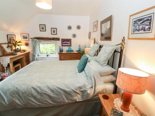 a bedroom with a bed and a desk with a lamp at Fell Cottage in Wigton