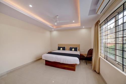 a bedroom with a bed and a large window at Townhouse OAK Ess Jay in Bangalore