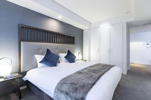 a bedroom with a large white bed with blue pillows at The Vale Niseko in Kutchan