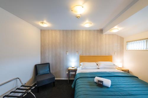 Habitación de hotel con cama y silla en Roma On Riccarton Motel, en Christchurch