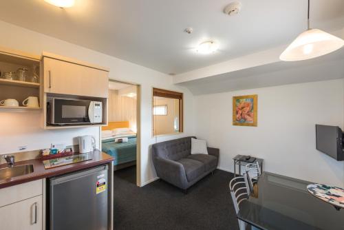 a room with a kitchen and a living room with a couch at Roma On Riccarton Motel in Christchurch