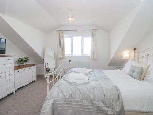 a white bedroom with a bed and a mirror at Driftwood Cottage Roa Island Piel Island in Barrow in Furness