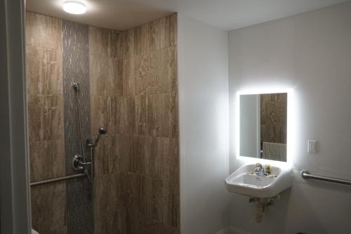 a bathroom with a sink and a shower with a mirror at Avenue Motel in Gardena