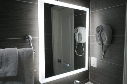 a mirror in a bathroom with a phone on the wall at Avenue Motel in Gardena