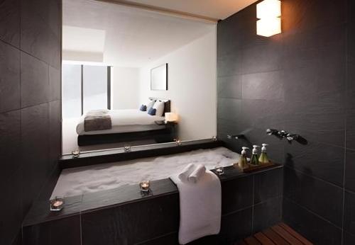 a bathroom with a large mirror and a bed at The Vale Niseko in Kutchan