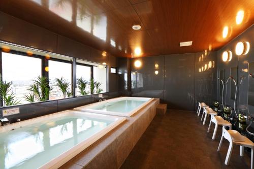 Hotel Montoview Yonezawa في يونيزاوا: حمام كبير مع حوض استحمام ساخن وكراسي
