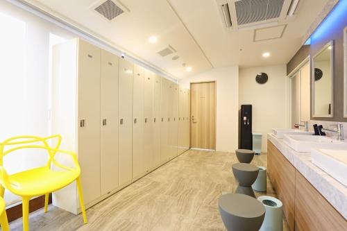 a bathroom with a sink and a yellow chair at Hotel Montoview Yonezawa in Yonezawa