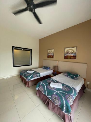 two beds in a room with a ceiling fan at Buluh Inn @ Gold Coast Morib in Banting
