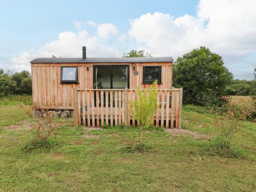 a wooden cabin in a field with a fence at The Bumblebee in Pembroke