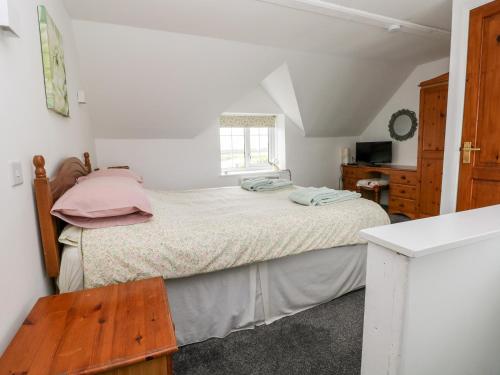 a bedroom with a bed with pink sheets and a window at No 2 New Cottages in Pembroke