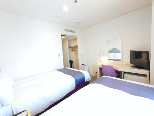 a bedroom with two beds and a desk with a computer at Hotel Montoview Yonezawa in Yonezawa