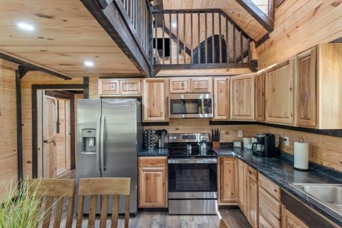 a kitchen with wooden cabinets and a stainless steel refrigerator at Private Cabin w King Bed and Private Hot Tub in Rogers