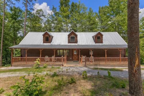 a log cabin in the woods with a porch at Private Cabin w King Bed and Private Hot Tub in Rogers