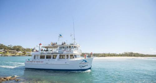 a boat in the water near a beach at Amazing Views - Belle Escapes Jervis Bay in Vincentia