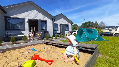 a baby playing in a sandbox in a yard at Domki Letniskowe Sarbilove in Sarbinowo