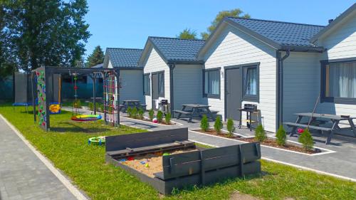 una casa con parque infantil en el patio en Domki Letniskowe Sarbilove en Sarbinowo