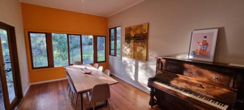 a dining room with a table and a piano at Emerald Retreat in Emerald