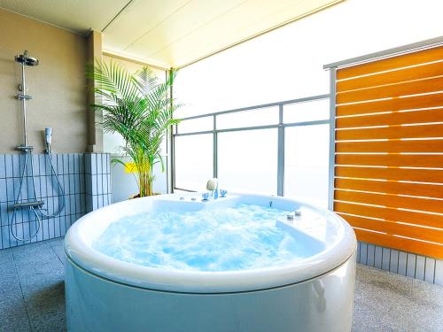 uma grande banheira numa casa de banho com uma grande janela em Hotel Seaside Shimabara em Shimabara