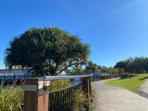 a fence with a tree on the side of a sidewalk at The Sebel Twin Waters in Twin Waters