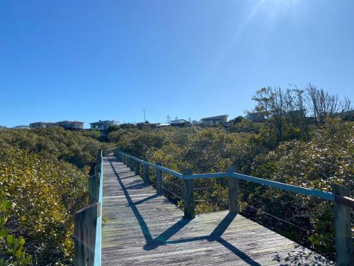 a wooden boardwalk in the middle of a beach at The Sebel Twin Waters in Twin Waters
