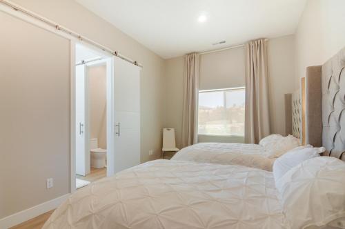 a white bedroom with a large bed and a window at Lake Powell Sunrise Villa by Antelope Canyon with firepit and scenic views in Big Water