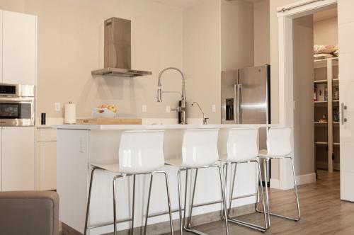 a kitchen with white counter chairs and a kitchen island at Lake Powell Sunrise Villa by Antelope Canyon with firepit and scenic views in Big Water