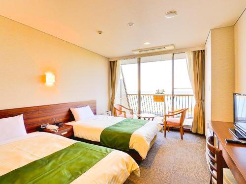 a hotel room with two beds and a television at Hotel Seaside Shimabara in Shimabara