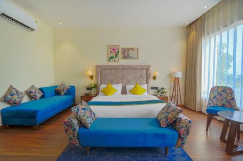 a bedroom with a bed and two blue couches at Hotel Escala By Levelup in Amritsar