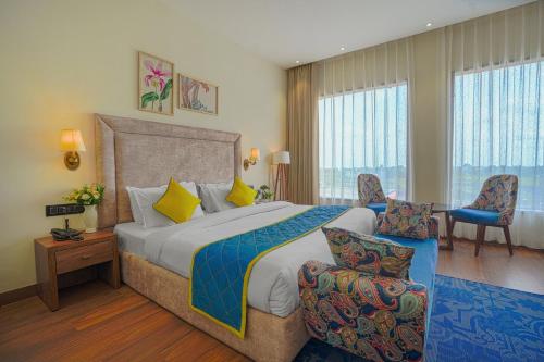 a hotel room with a bed and chairs and windows at Hotel Escala By Levelup in Amritsar
