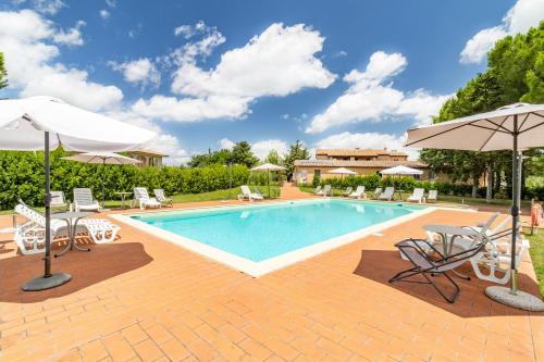 una piscina con sillas y sombrillas junto a en Family Apartments With Pool Near Volterra - Happy Rentals, en Pomarance