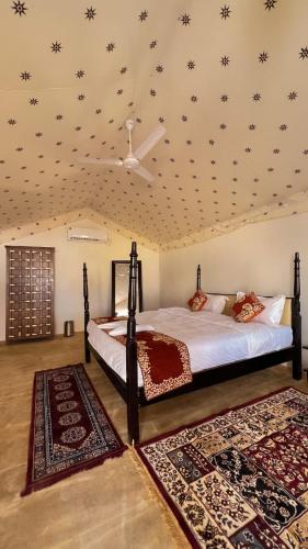 a bedroom with a bed and two rugs at Excellent Desert Safari camp in Sām