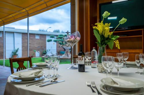 a table with plates and glasses and a bottle of wine at Hotel Bartos in Almussafes