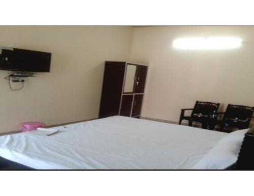 1 dormitorio con 1 cama con sillas y TV en Hotel Mamta Palace, Kushinagar, en Kushinagar