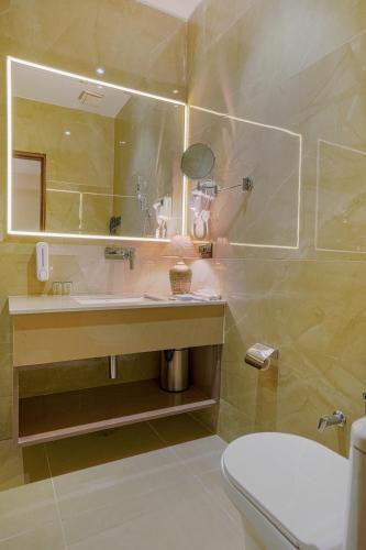 a bathroom with a sink and a mirror and a toilet at Hotel Escala By Levelup in Amritsar