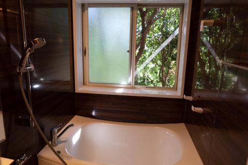 a bathroom with a bath tub and a window at Villa Yumigahama in Minamiizu