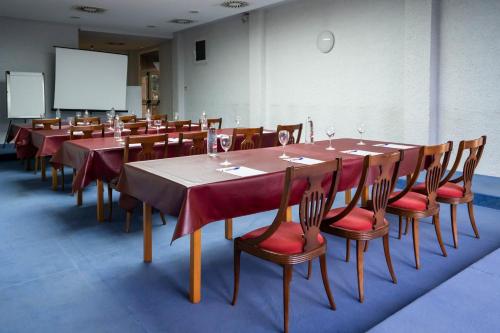a conference room with long tables and chairs and a screen at Hotel Bartos in Almussafes