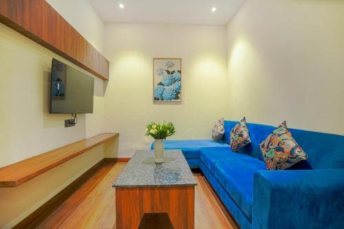 a living room with a blue couch and a tv at Hotel Escala By Levelup in Amritsar