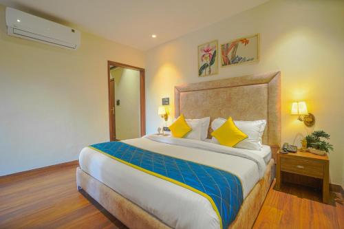 a hotel room with a large bed with yellow pillows at Hotel Escala By Levelup in Amritsar