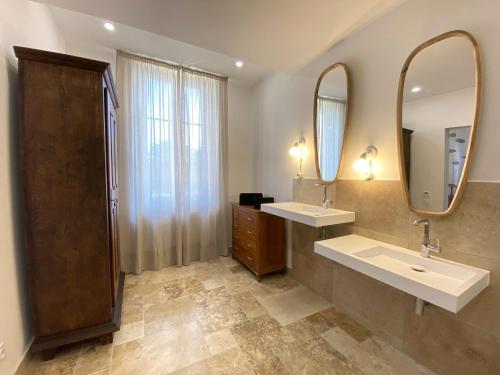 a bathroom with two sinks and two mirrors at Domaine de Lanis - Maison d'hôtes avec parc et piscine in Castelnaudary