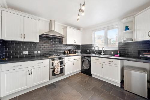 a kitchen with white cabinets and a washer and dryer at Detached House in Ashford with Free Parking and Hot Tub - Sleeps 10 in Ashford