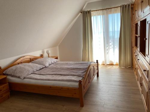 um quarto com uma cama e uma grande janela em Paphegy Apartman em Balatongyörök