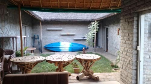 a patio with two tables and a blue boat in the yard at Vamoose Hampi Homestay Otters Island in Hampi