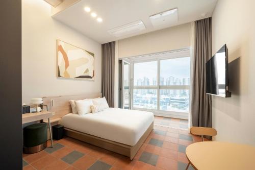 a hotel room with a bed and a large window at Le collective Siheung Wavepark in Siheung