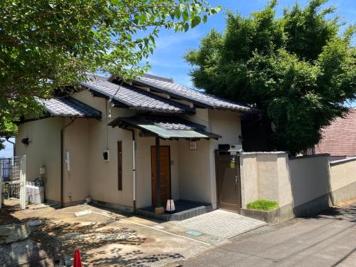 a small white house with an awning on a street at 熱海の海が一望できる温泉付貸別荘 満月あじろ mitsukiajiro in Atami