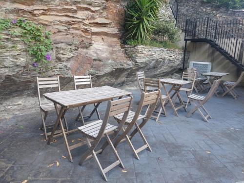 a group of wooden tables and chairs next to a stone wall at ALBERGUE CASTELOS in Lorenzana