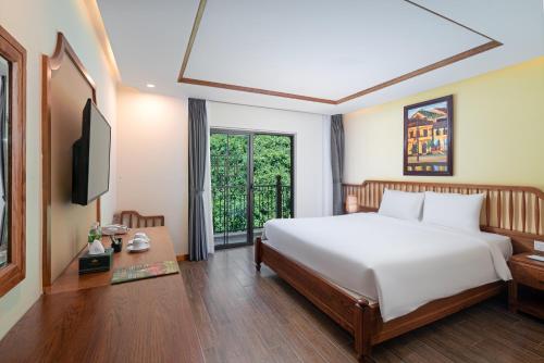 a bedroom with a white bed and a television at Fivitel Cổng Trời Đông Giang - Fivitel Đông Giang Heaven's Gate in Dong Giang