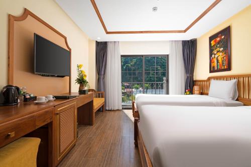 a hotel room with two beds and a television at Fivitel Cổng Trời Đông Giang - Fivitel Đông Giang Heaven's Gate in Dong Giang