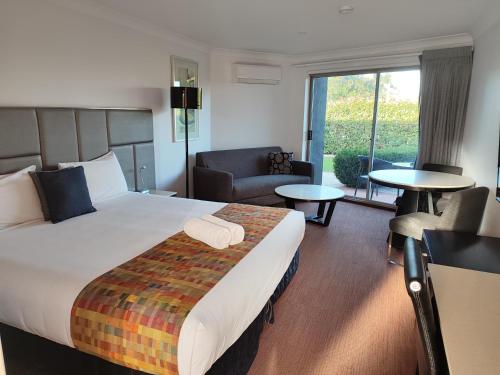 a hotel room with a large bed and a living room at Country Capital Motel in Tamworth