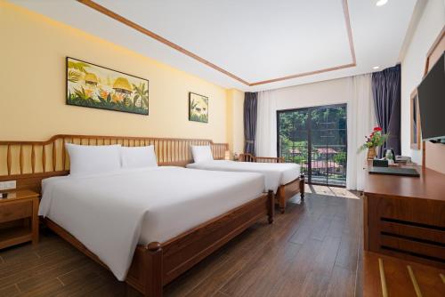 a hotel room with two beds and a television at Fivitel Cổng Trời Đông Giang - Fivitel Đông Giang Heaven's Gate in Dong Giang